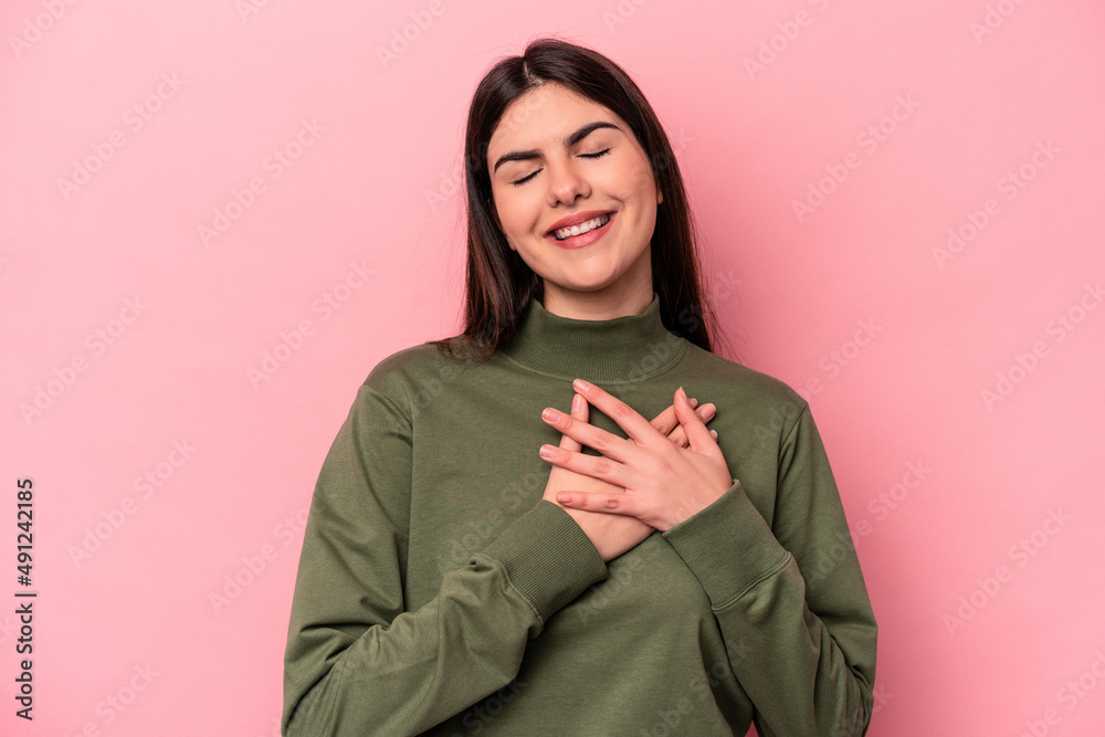 Young caucasian woman isolated on pink background has friendly expression, pressing palm to chest. Love concept. Young caucasian woman isolated on pink background has friendly expression, pressing palm to chest. Love concept.