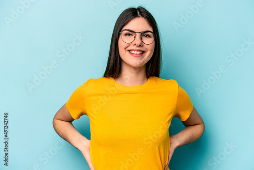 Young caucasian woman isolated on blue background confident keeping hands on hips.