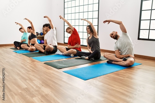 Group of young people concentrate training yoga at sport center.