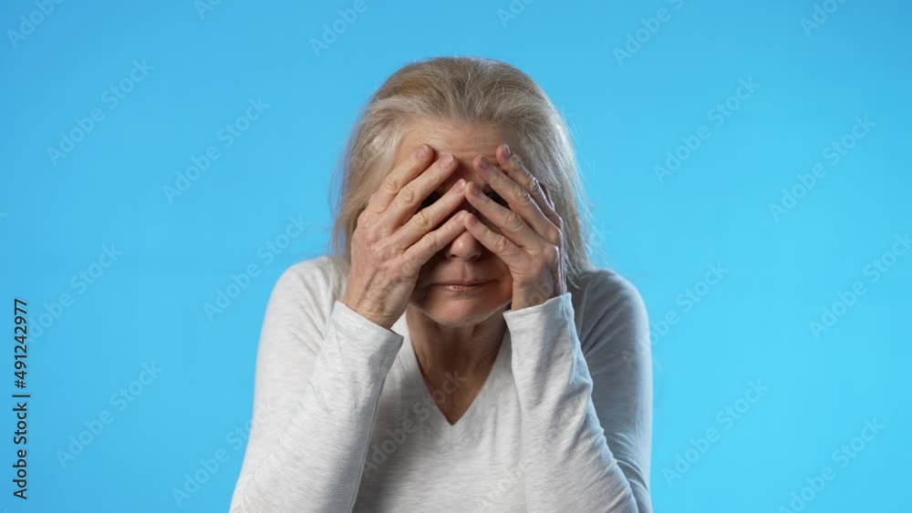 Portrait of shocked worried scared blonde mature woman covering eyes with hands, isolated on blue background studio. People lifestyle concept. Portrait of shocked worried scared blonde mature woman covering eyes with hands, isolated on blue background studio. People lifestyle concept.