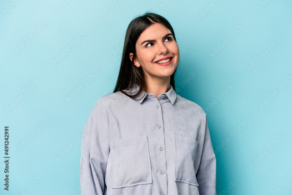 Young caucasian woman isolated on blue background relaxed and happy laughing, neck stretched showing teeth. Young caucasian woman isolated on blue background relaxed and happy laughing, neck stretched showing teeth.