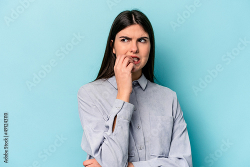 Young caucasian woman isolated on blue background biting fingernails, nervous and very anxious.