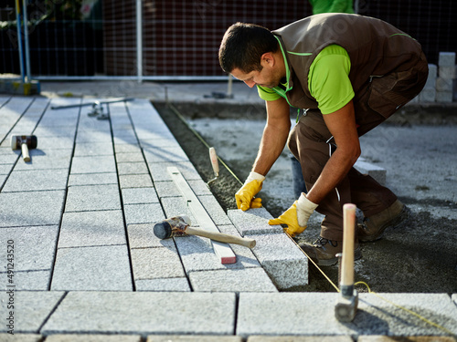 Construction worker arranging paving stones on sidewalk photo