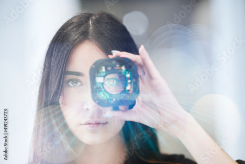 Young businesswoman looking through open camera lens at office photo