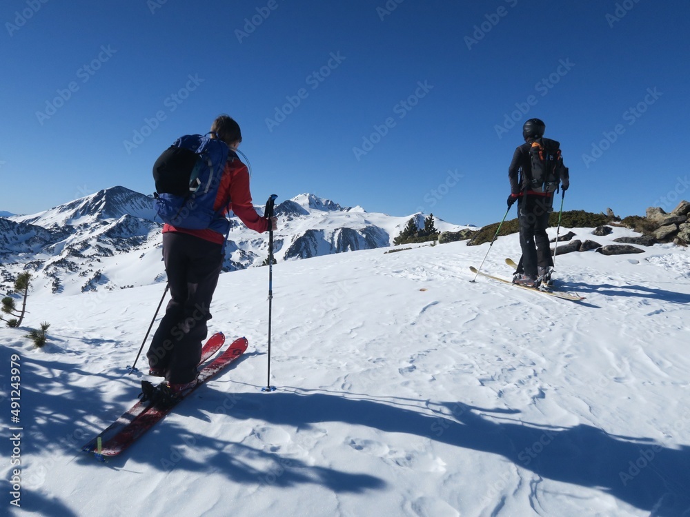 Couple homme femme en randonnée en ski de rando en montagne en hiver dans la neige des Pyrénées orientales catalanes sous le soleil