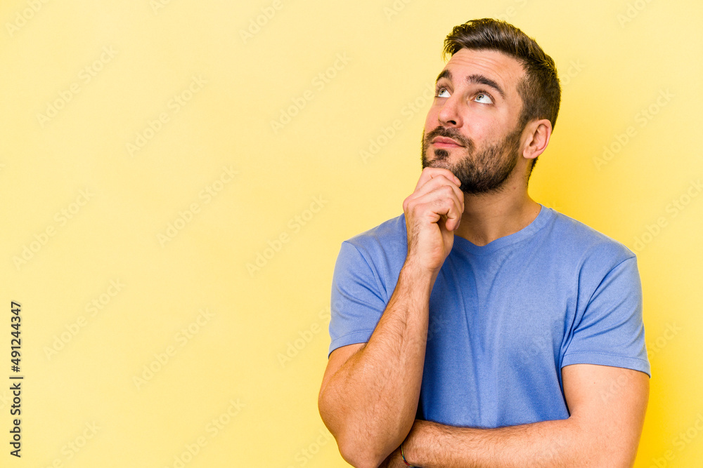 Young caucasian man isolated on yellow background looking sideways with doubtful and skeptical expression. Young caucasian man isolated on yellow background looking sideways with doubtful and skeptical expression.