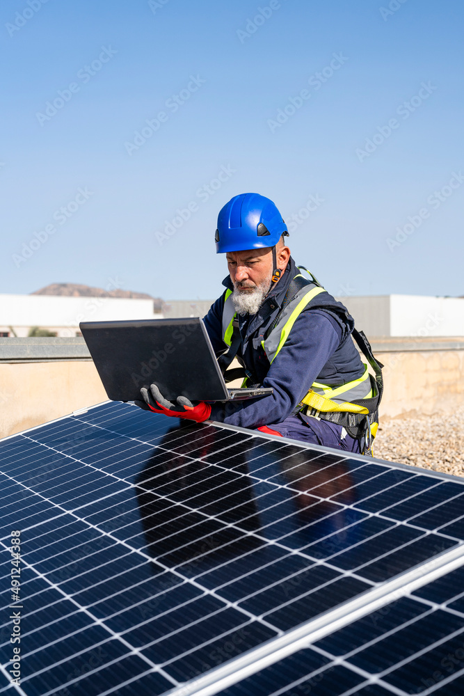Engineer working on laptop by solar panels Engineer working on laptop by solar panels