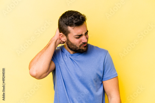 Young caucasian man isolated on yellow background suffering neck pain due to sedentary lifestyle. © Asier