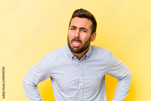 Young caucasian man isolated on yellow background funny and friendly sticking out tongue.