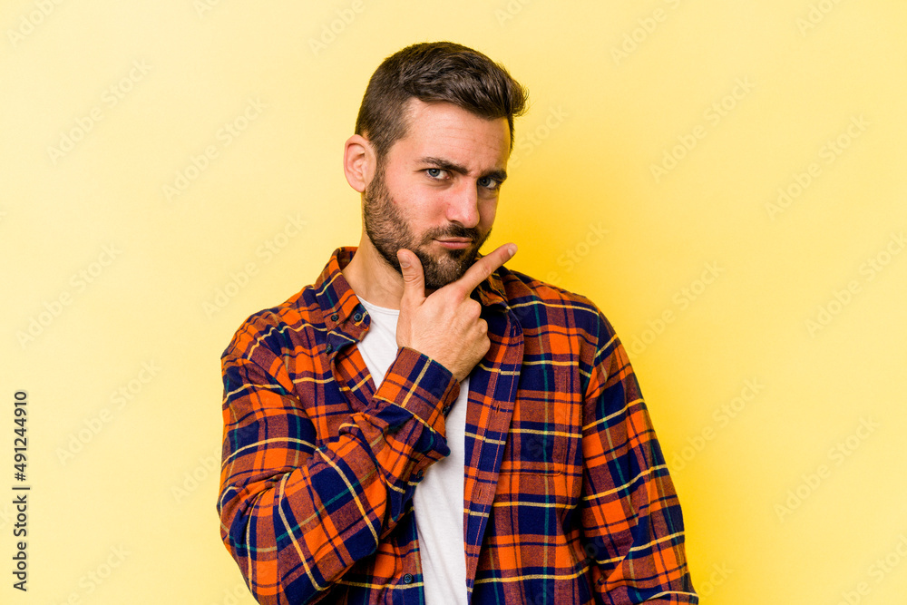 Young caucasian man isolated on yellow background contemplating, planning a strategy, thinking about the way of a business.