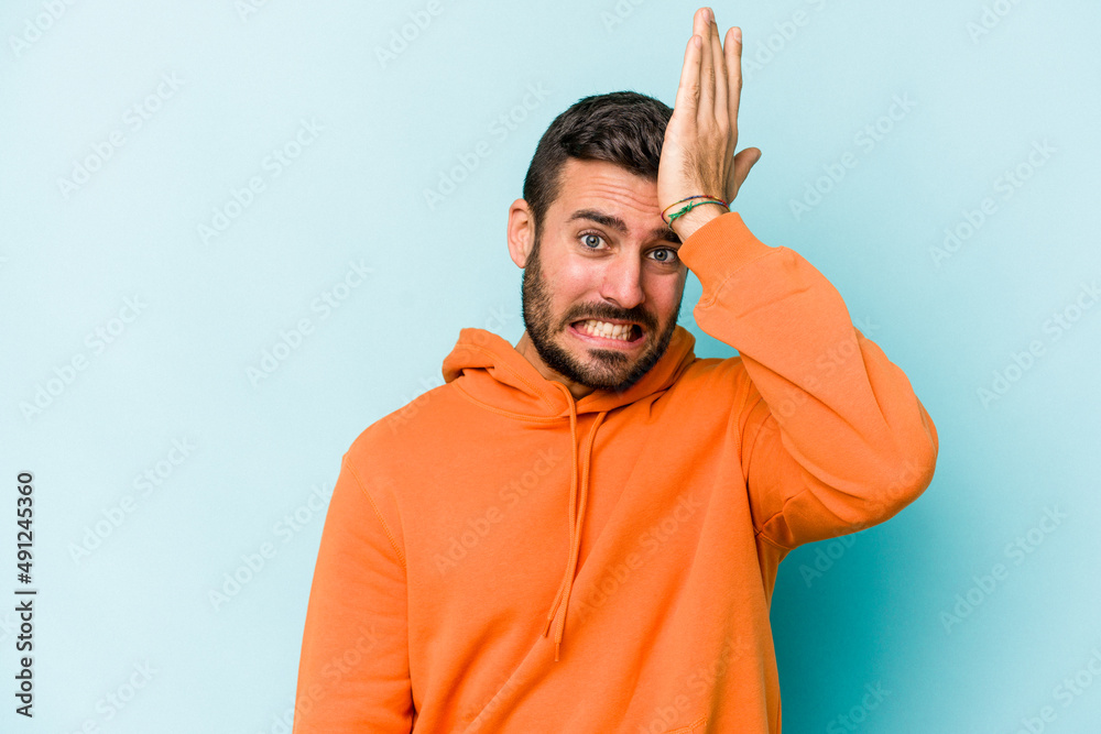 Young caucasian man isolated on blue background forgetting something, slapping forehead with palm and closing eyes.