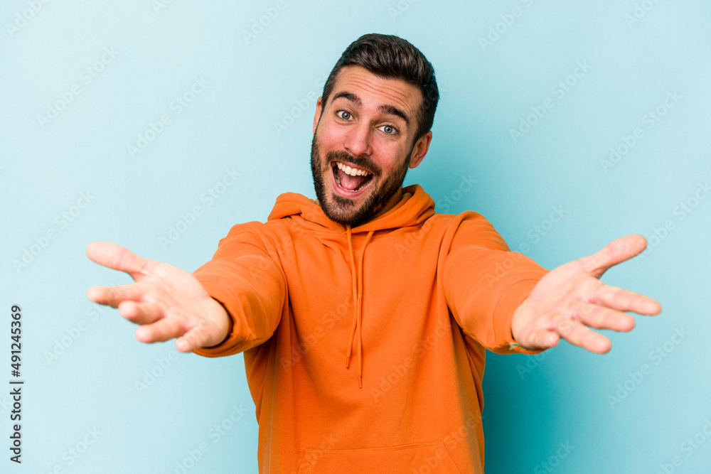 Young caucasian man isolated on blue background showing a welcome expression. Young caucasian man isolated on blue background showing a welcome expression.