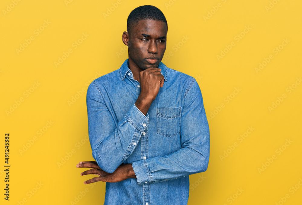 Young african american man wearing casual clothes with hand on chin thinking about question, pensive expression. smiling with thoughtful face. doubt concept. Young african american man wearing casual clothes with hand on chin thinking about question, pensive expression. smiling with thoughtful face. doubt concept.