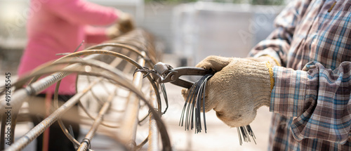 Φωτογραφία Construction worker hands securing steel bars with wire rod for reinforcement of concrete