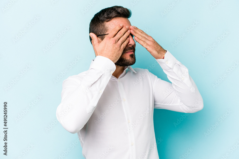 Young caucasian man isolated on blue background afraid covering eyes with hands. Young caucasian man isolated on blue background afraid covering eyes with hands.