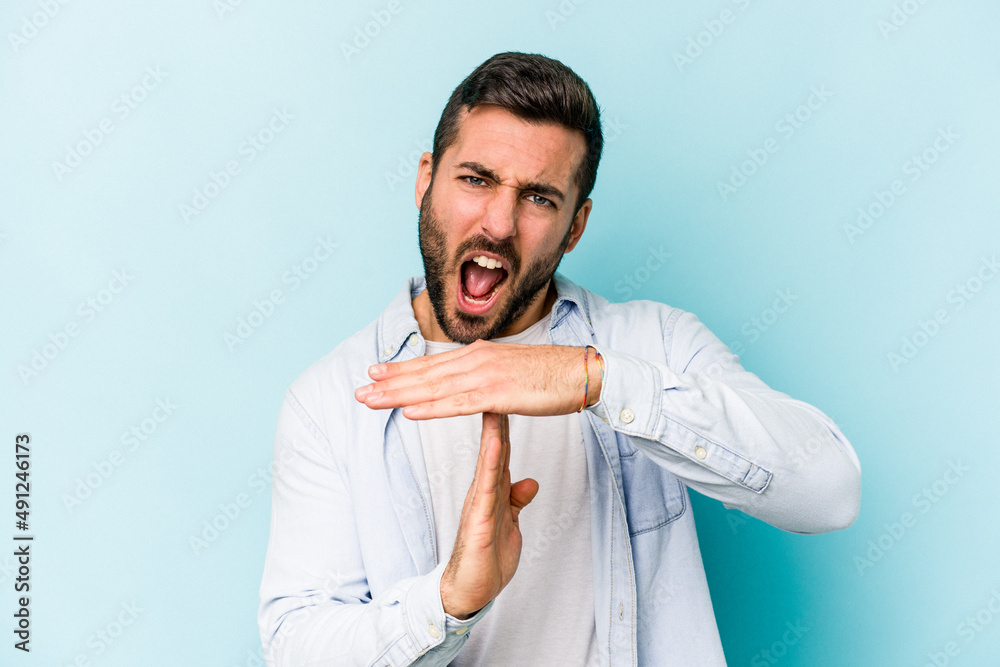 Young caucasian man isolated on blue background showing a timeout gesture.