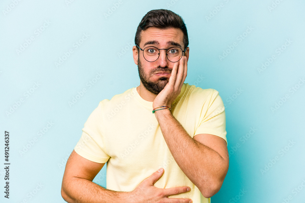 Young caucasian man isolated on blue background blows cheeks, has tired expression. Facial expression concept. Young caucasian man isolated on blue background blows cheeks, has tired expression. Facial expression concept.
