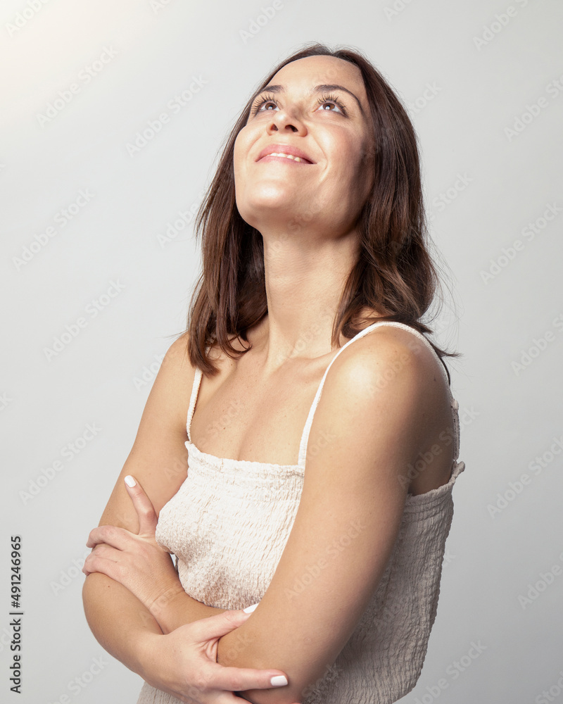 Smiling woman with arms crossed day dreaming in studio Smiling woman with arms crossed day dreaming in studio