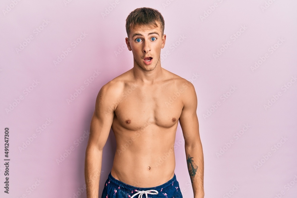 Fototapeta premium Young caucasian man wearing swimwear afraid and shocked with surprise expression, fear and excited face.