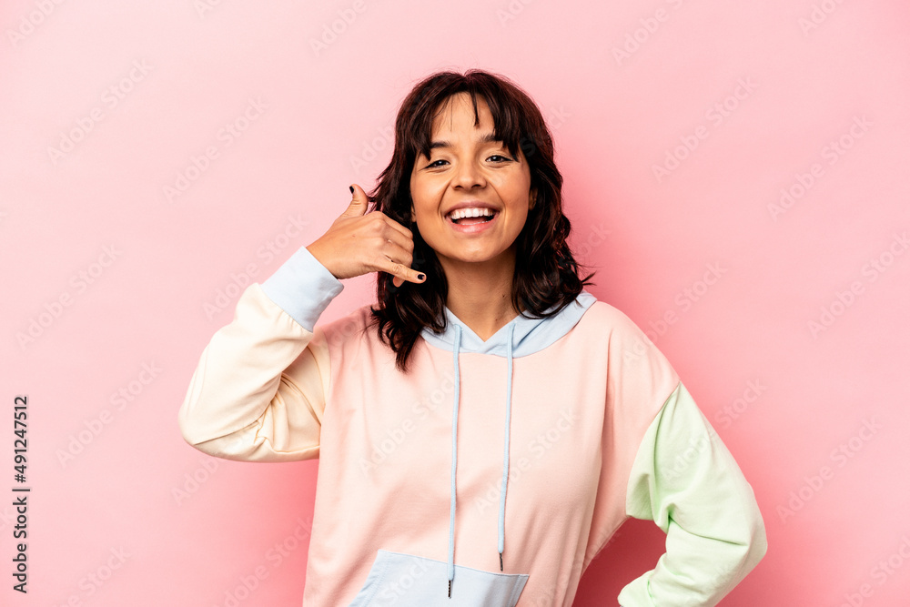 Young hispanic woman isolated on pink background showing a mobile phone call gesture with fingers. Young hispanic woman isolated on pink background showing a mobile phone call gesture with fingers.