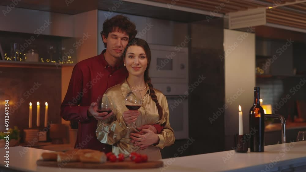 Loving couple looking at camera while embracing on kitchen Loving couple looking at camera while embracing on kitchen