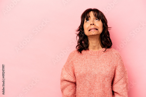 Young hispanic woman isolated on pink background shouting very angry, rage concept, frustrated.