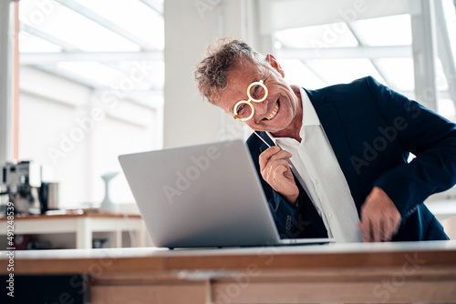 Cheerful businessman with lorgnette on video call over laptop