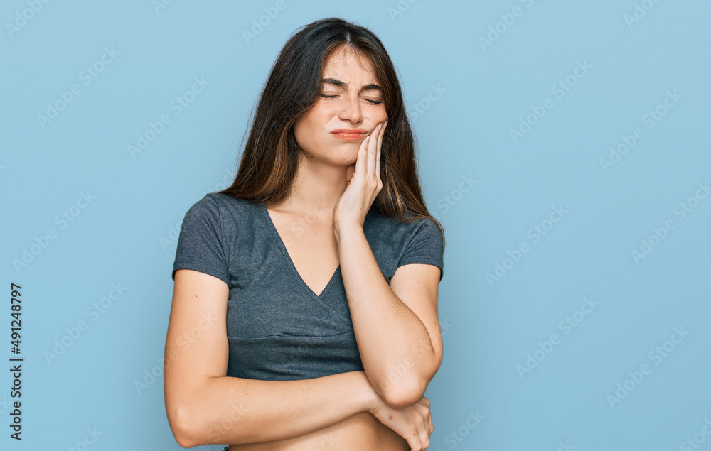 Young beautiful teen girl wearing casual crop top t shirt touching mouth with hand with painful expression because of toothache or dental illness on teeth. dentist Young beautiful teen girl wearing casual crop top t shirt touching mouth with hand with painful expression because of toothache or dental illness on teeth. dentist
