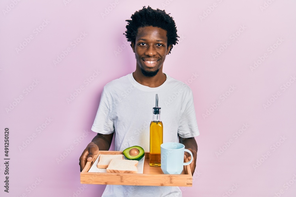 Young african american man holding tray with breakfast food smiling with a happy and cool smile on face. showing teeth. Young african american man holding tray with breakfast food smiling with a happy and cool smile on face. showing teeth.