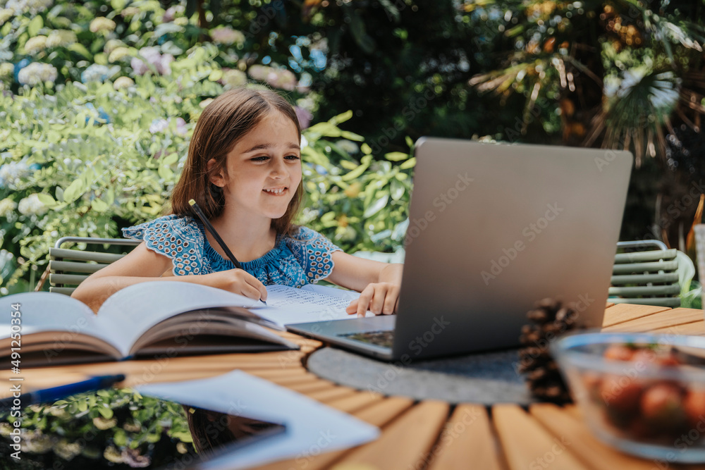 Smiling girl e-learning through laptop at back yard Smiling girl e-learning through laptop at back yard