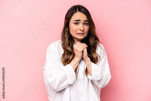 Young caucasian woman isolated on pink background scared and afraid.