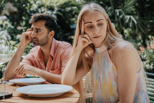 Couple ignoring each other at outdoor table photo