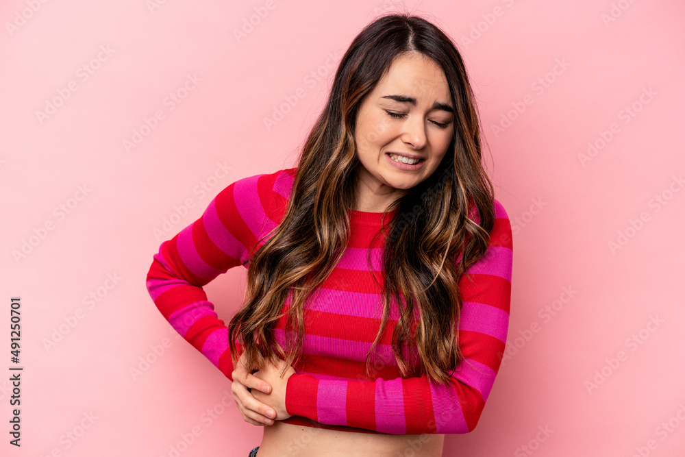 Young caucasian woman isolated on pink background having a liver pain, stomach ache. Young caucasian woman isolated on pink background having a liver pain, stomach ache.