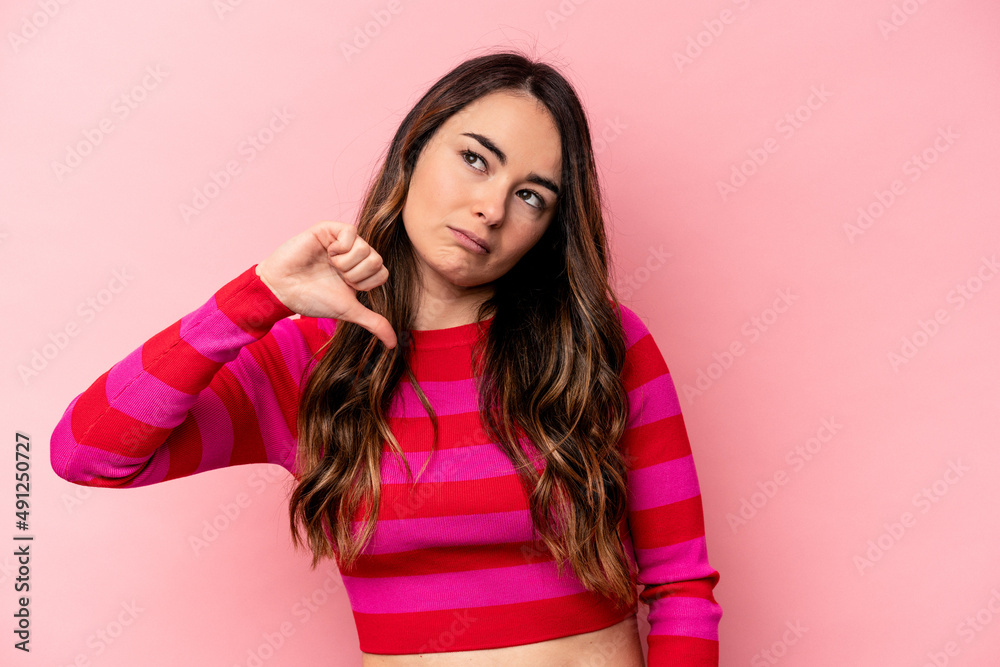 Young caucasian woman isolated on pink background showing a dislike gesture, thumbs down. Disagreement concept. Young caucasian woman isolated on pink background showing a dislike gesture, thumbs down. Disagreement concept.