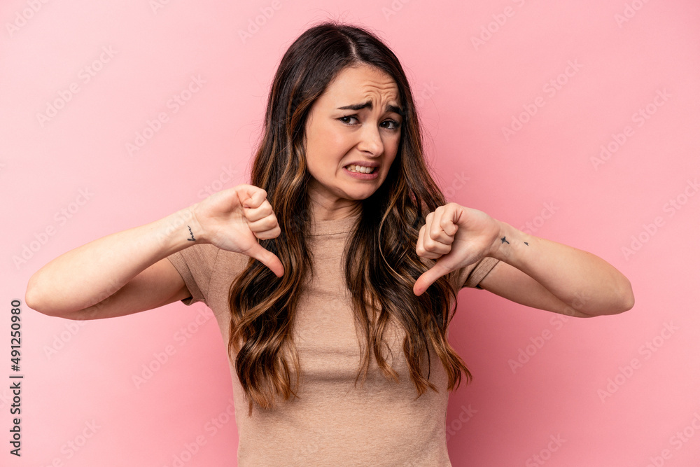 Young caucasian woman isolated on pink background showing thumb down, disappointment concept. Young caucasian woman isolated on pink background showing thumb down, disappointment concept.