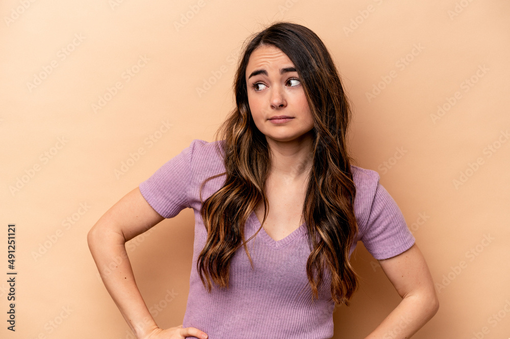 Young caucasian woman isolated on beige background confused, feels doubtful and unsure. Young caucasian woman isolated on beige background confused, feels doubtful and unsure.