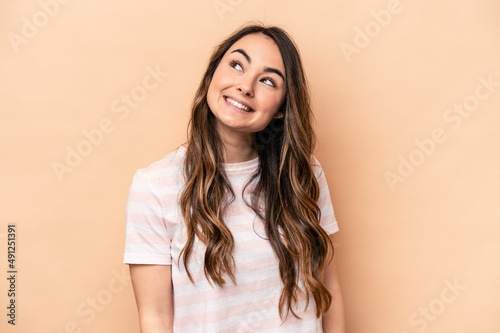 Young caucasian woman isolated on beige background relaxed and happy laughing, neck stretched showing teeth.