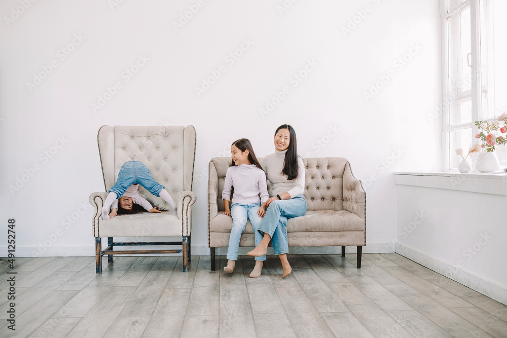 Happy mother with daughters sitting on sofa in living room Happy mother with daughters sitting on sofa in living room