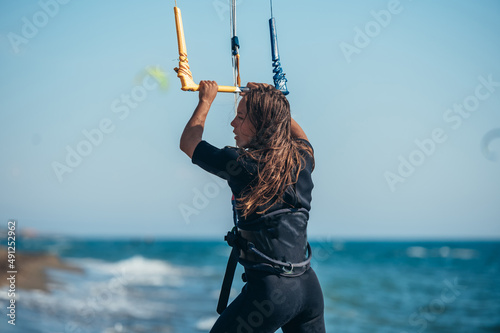 Young sporty woman using control bar to lift her kite up for kitesurfing