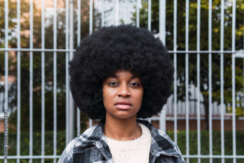 Serious woman with afro hairstyle in front of fence photo