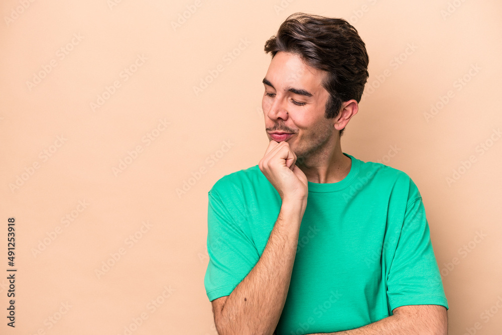 Young caucasian man isolated on beige background looking sideways with doubtful and skeptical expression. Young caucasian man isolated on beige background looking sideways with doubtful and skeptical expression.