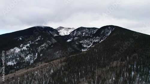 Drone shot revealing a snow covered mountain peak amongst the clouds photo