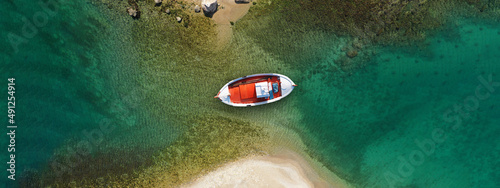 Aerial drone ultra wide top view photo of traditional red fishing boat anchored in exotic Ionian destination island with emerald sea, Greece