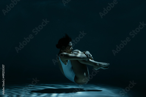 Woman in fetal position swimming underwater photo