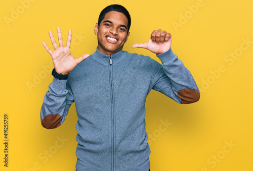 Young handsome hispanic man wearing casual sweatshirt showing and pointing up with fingers number six while smiling confident and happy.
