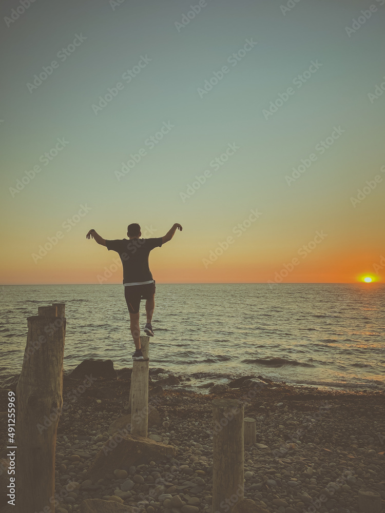 Man doing the Crane Kick at sunset He practiced the crane kick while standing on a stump.