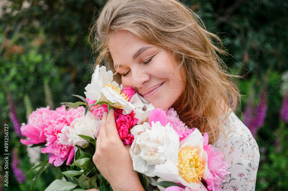 Smiling blond woman with eyes closed hugging flowers Smiling blond woman with eyes closed hugging flowers