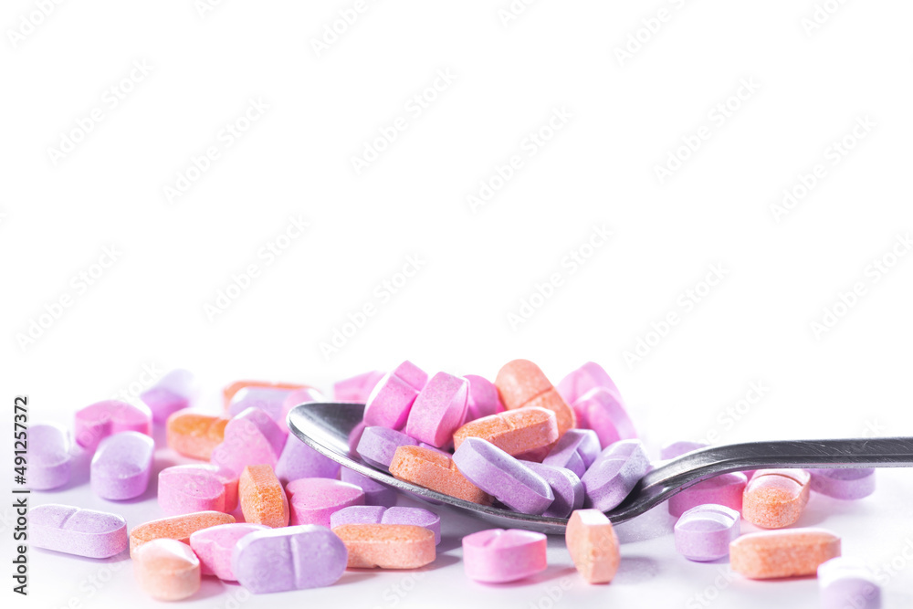Closeup shot of spoon and pile of pills on white background. Closeup shot of spoon and pile of pills on white background.