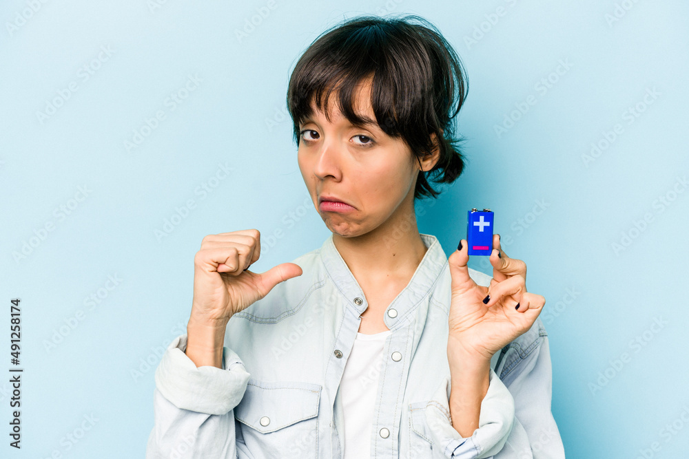 Young hispanic woman holding a batterie isolated on blue background feels proud and self confident, example to follow. Young hispanic woman holding a batterie isolated on blue background feels proud and self confident, example to follow.