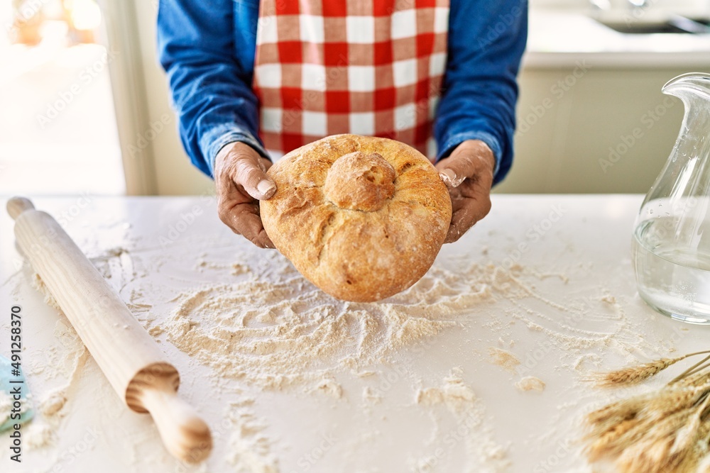 Senior man holding homemade bread at kitchen Senior man holding homemade bread at kitchen